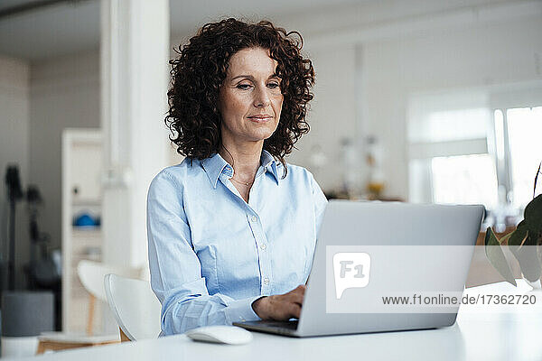 Reife Geschäftsfrau mit Laptop am Schreibtisch im Büro