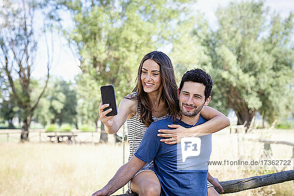 Smiling woman taking selfie with boyfriend