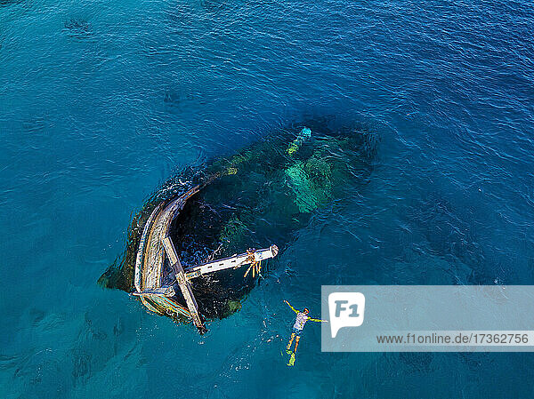 Luftaufnahme eines einsamen Mannes beim Schnorcheln um ein versunkenes Schiffswrack