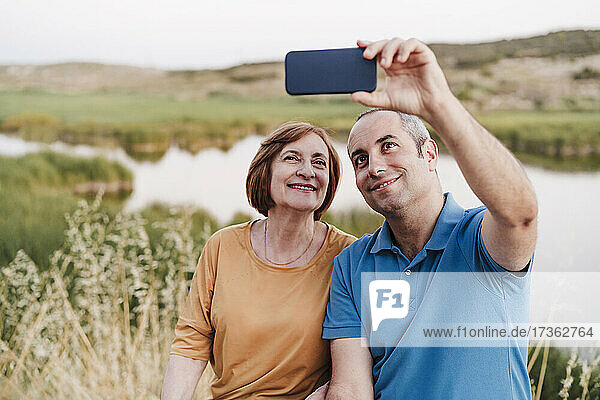 Sohn und Mutter nehmen Selfie durch Smartphone in der Nähe von See