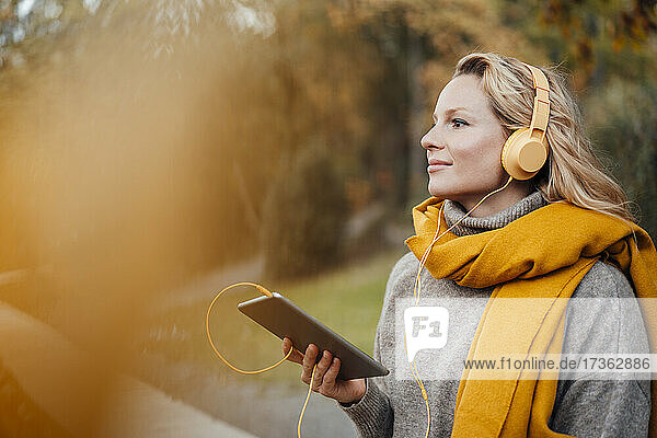 Frau hört im Herbst Musik über Kopfhörer
