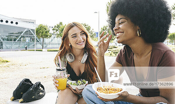 Glückliche multiethnische Freundinnen unterhalten sich beim Essen