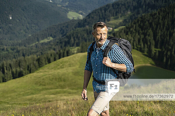 Älterer Mann mit Rucksack beim Wandern auf einem Berg