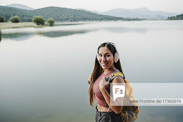 Smiling female backpacker standing by lake