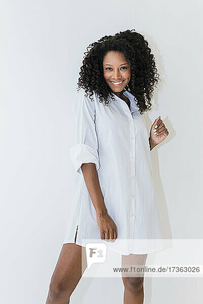 Young Afro woman in dress against white background