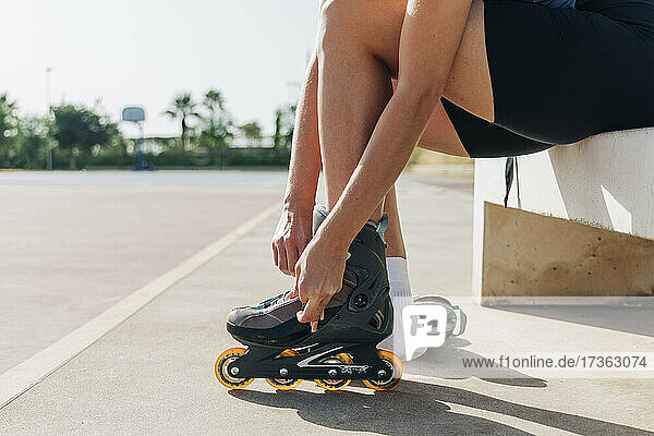 Frau mit Inline-Skates auf einem Basketballplatz an einem sonnigen Tag
