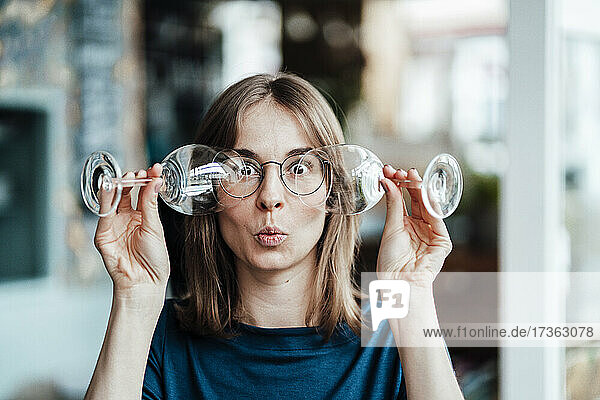 Young woman looking through wineglasses in cafe