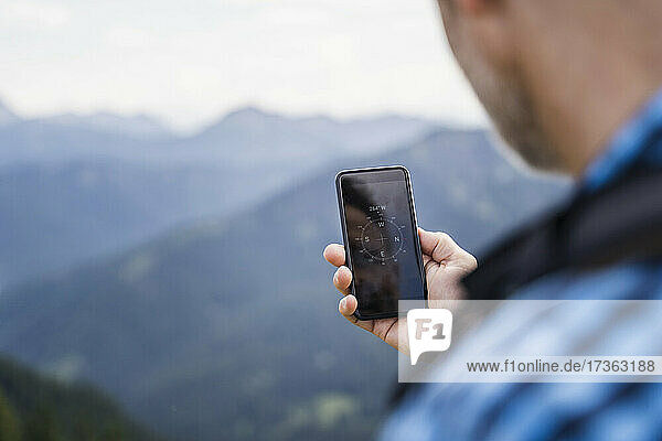 Male hiker searching direction through mobile phone