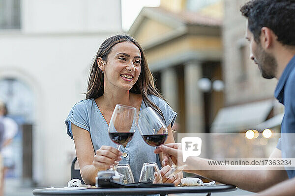 Couple toasting wine while sitting at sidewalk cafe