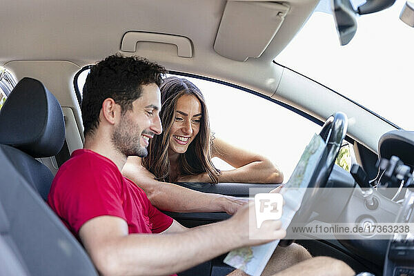 Lächelndes Paar  das während eines Ausflugs über die Karte diskutiert