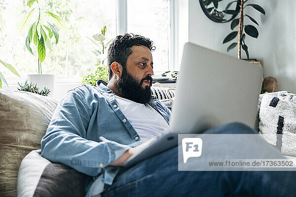 Mature man using laptop while sitting on sofa