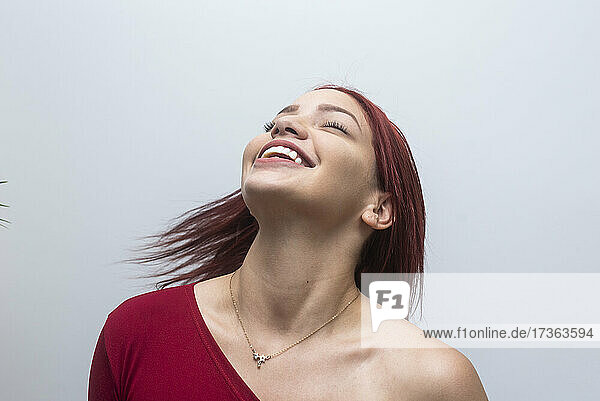 Smiling woman with eyes closed in front of white background