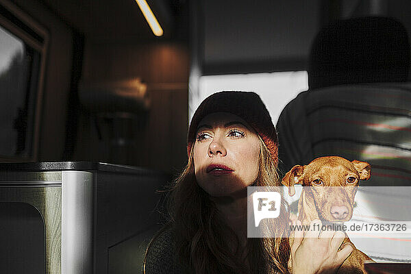 Nachdenklich dreinblickende Frau mit Hund im Lieferwagen