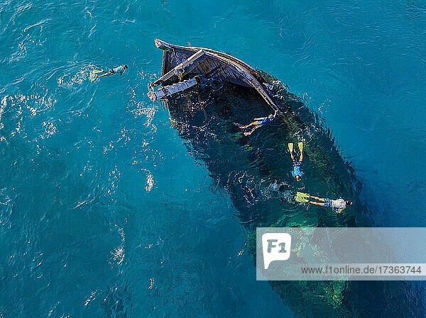Luftaufnahme von vier Männern beim Schnorcheln um ein versunkenes Schiffswrack