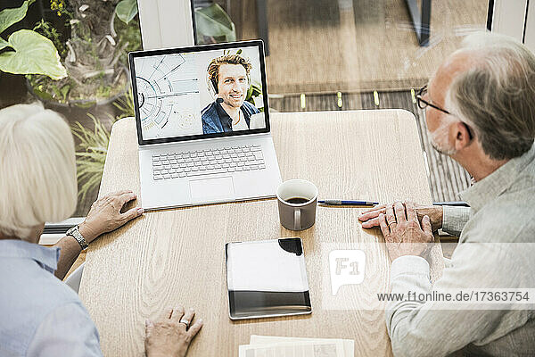 Reife Geschäftsleute führen einen Videoanruf mit einem männlichen Kollegen am Laptop im Büro zu Hause