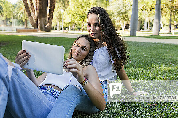 Junge Freundinnen benutzen ein digitales Tablet in einem öffentlichen Park