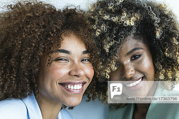 Lächelnde multiethnische Kolleginnen mit lockigem Haar