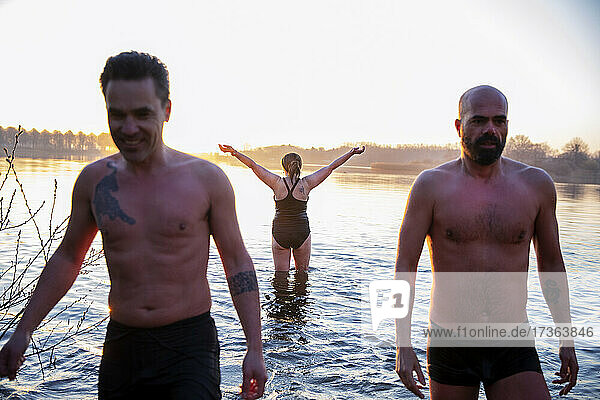 Hemdlose Männer stehen im Fluss mit einer Freundin im Hintergrund