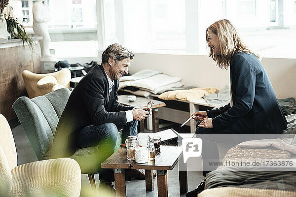Glücklicher Geschäftsmann und Geschäftsfrau lachen  während sie in einem Café miteinander diskutieren