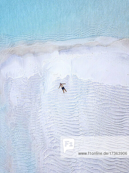 Luftaufnahme eines einsamen Mannes beim Sonnenbaden am Sandstrand der Insel Thulusdhoo
