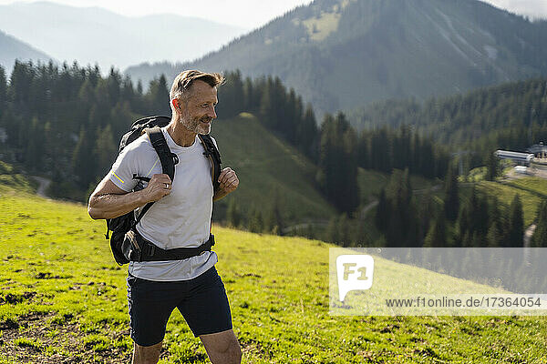 Smiling man with backpack hiking on mountain