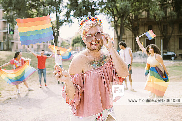 Lächelnder schwuler Mann mit Flagge im Park stehend