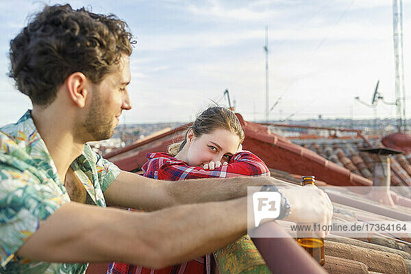 Young woman leaning on railing by boyfriend at rooftop