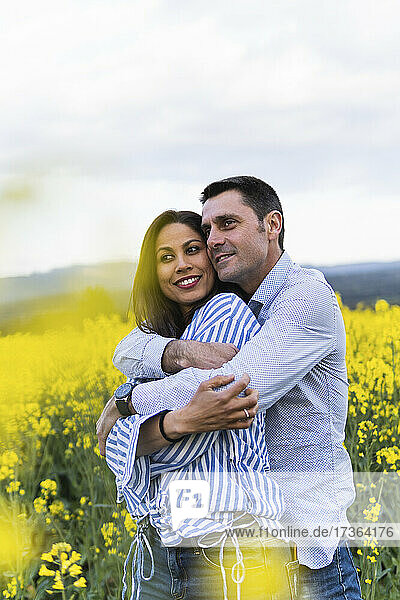 Mann umarmt Frau  während er in einem gelben Feld steht