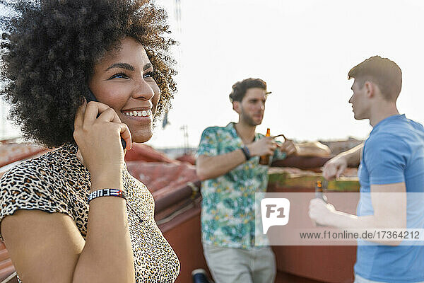 Lächelnde junge Frau  die auf einer Wochenendparty mit ihrem Smartphone telefoniert