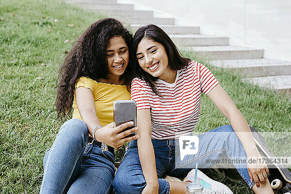 Lesbisches Paar  das ein Selfie mit seinem Smartphone macht  während es im Park sitzt