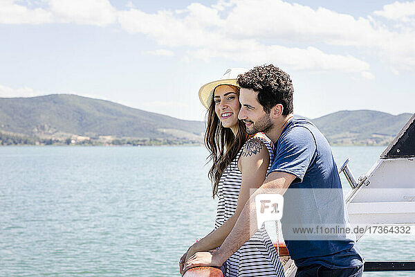 Couple leaning on tourboat railing during sunny day