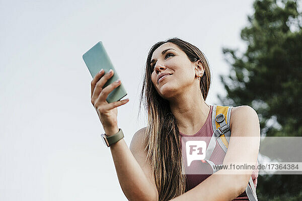 Woman holding smart phone while looking away