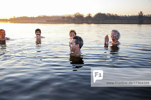 Lächelnde männliche und weibliche Freunde  die sich im kalten Wasser vergnügen