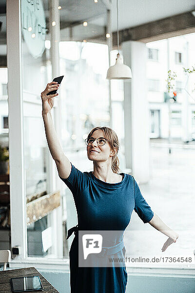 Junge Geschäftsfrau nimmt Selfie durch Smartphone im Café