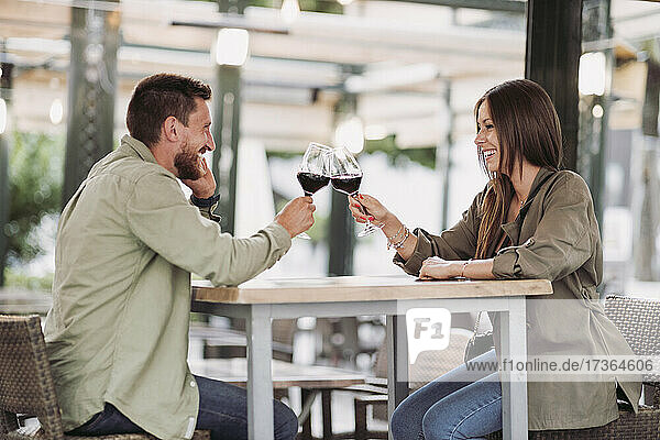 Mid adult couple toasting wine while sitting at bar
