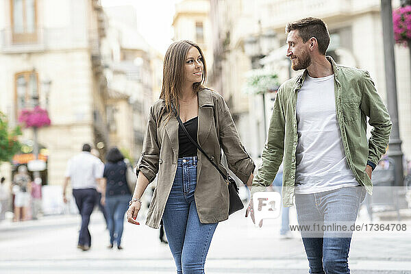 Paar hält sich an den Händen  während es auf der Straße spazieren geht