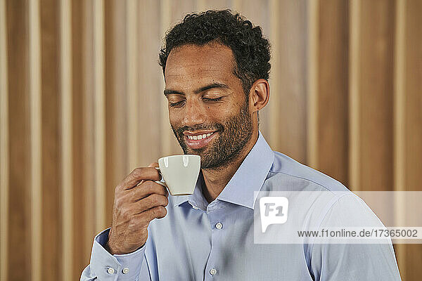 Lächelnde männliche Fachkraft hält Kaffeetasse im Büro