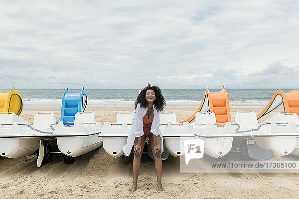 Fröhliche Frau lehnt sich am Strand an ein Boot