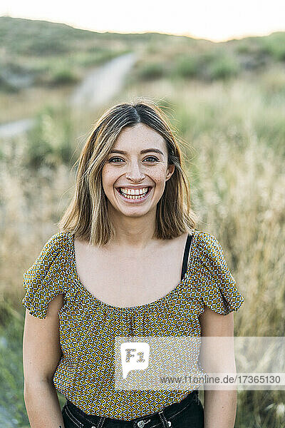 Junge Frau lächelt  während sie auf einem Feld steht