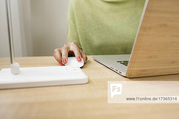 Frau benutzt Computermaus bei der Arbeit am Laptop