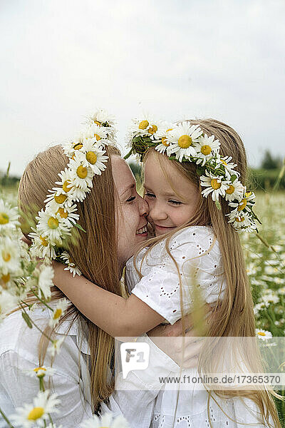 Lächelnde Mutter und Tochter mit Blumen auf einem Feld