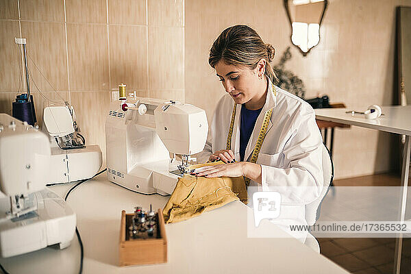 Junge Modeexpertin beim Nähen von Stoffen mit der Maschine in einem Workshop