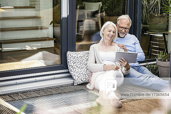 Woman using digital tablet while sitting by man at balcony