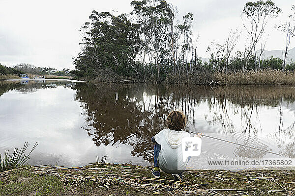 Young boy sitting on a river bank