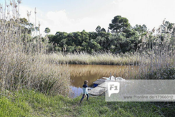Young boy playing near a lagoon on the Klein River estuary  boat moored at a dock