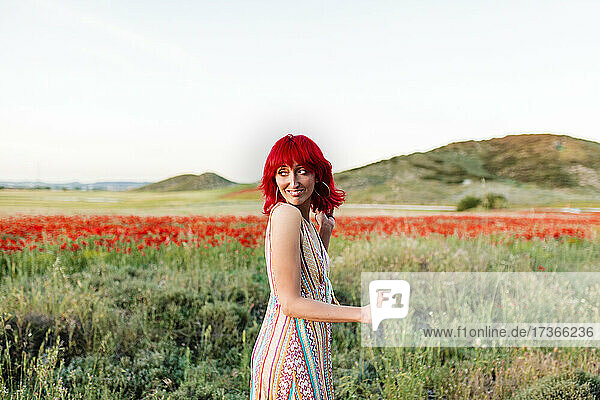 Redheaded woman looking over shoulder in poppy field