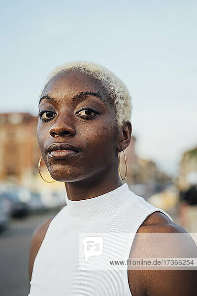 Young woman with short white hair staring