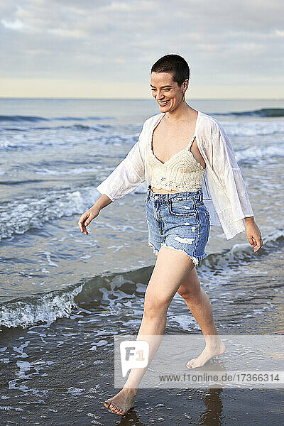 Junge Frau lächelt beim Spaziergang am Strand