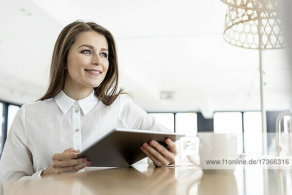 Nachdenkliche weibliche Fachkraft mit digitalem Tablet im Büro