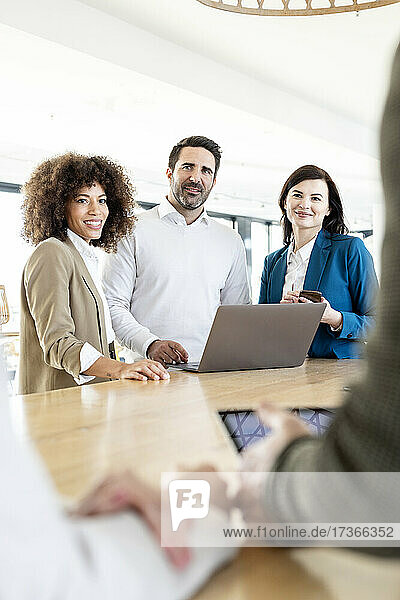 Businessman and businesswomen looking at colleagues discussing strategy during meeting in office